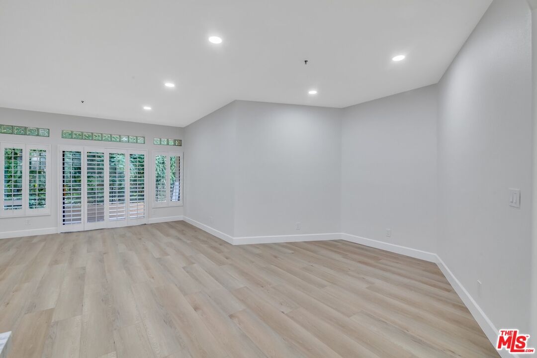 4477 Woodman Avenue, Unit 207 Sherman Oaks, CA 91423 - Photo 8 of 34 a view of an empty room with wooden floor and a window