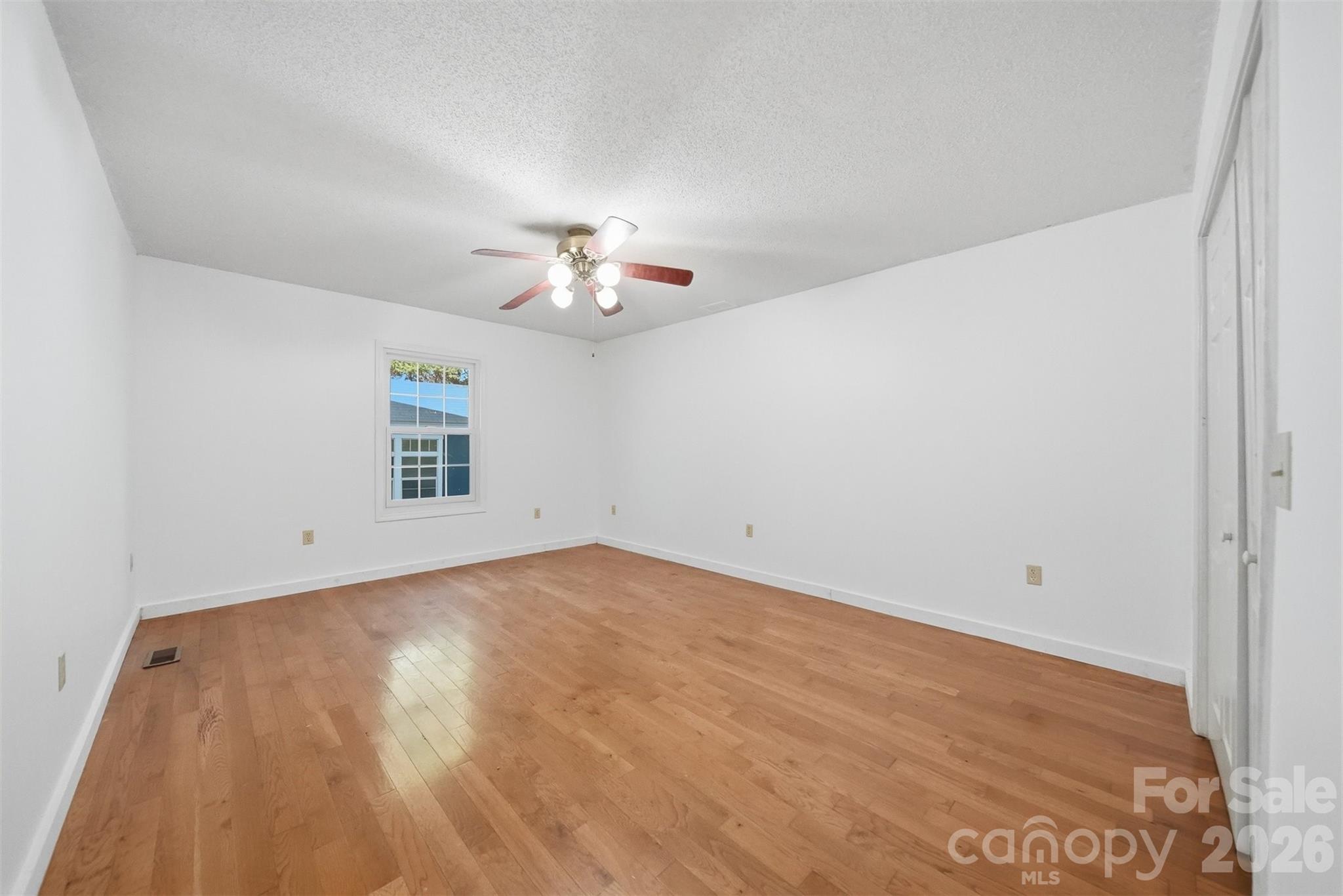 4771 Petra Mill Road Granite Falls, NC 28630 - Photo 31 of 46 an empty room with a chandelier fan and wooden floor