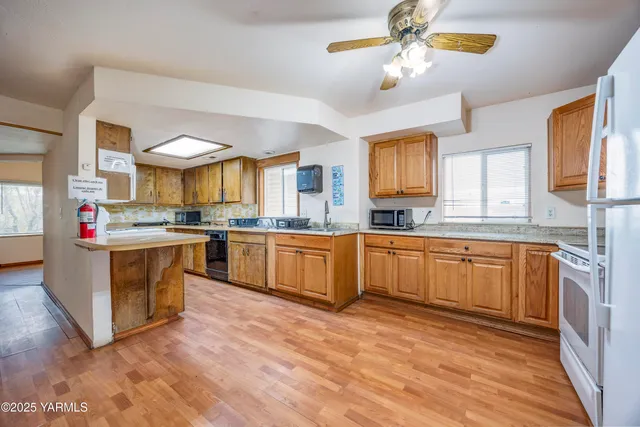 a kitchen with stainless steel appliances granite countertop a sink dishwasher a stove and a refrigerator with wooden floor