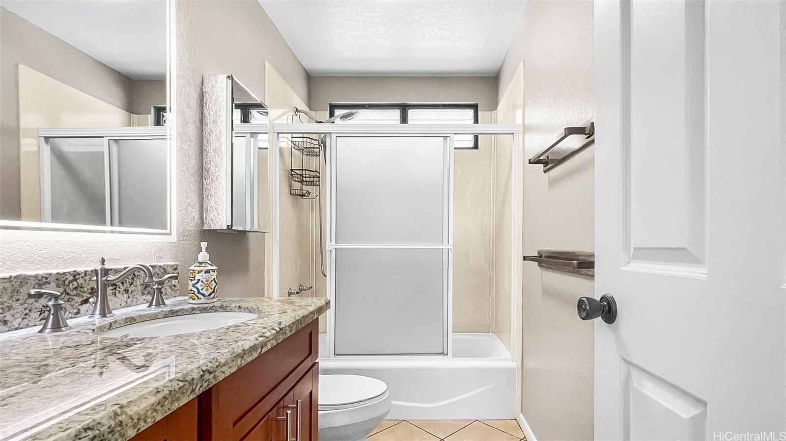 98-1421 Onikiniki Place, Unit 5 Aiea, HI 96701 - Photo 16 of 23 a bathroom with a granite countertop sink toilet and shower