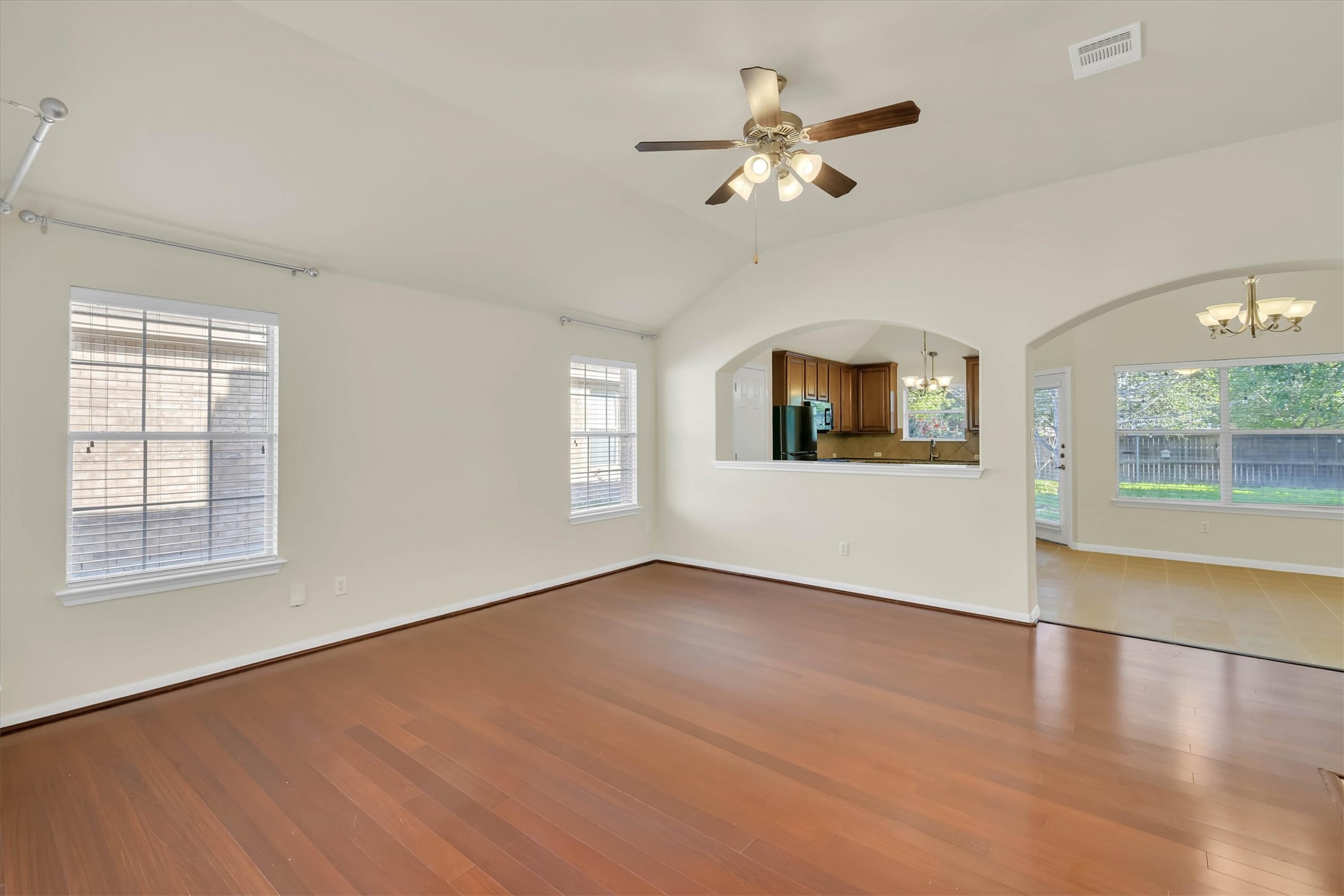 18420 Masi Loop Pflugerville, TX 78660 - Photo 4 of 33 Spacious living area featuring rich wood-finish flooring, a vaulted ceiling, and dual windows with blinds