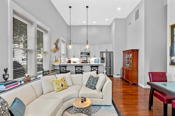 a living room with furniture kitchen view and a chandelier