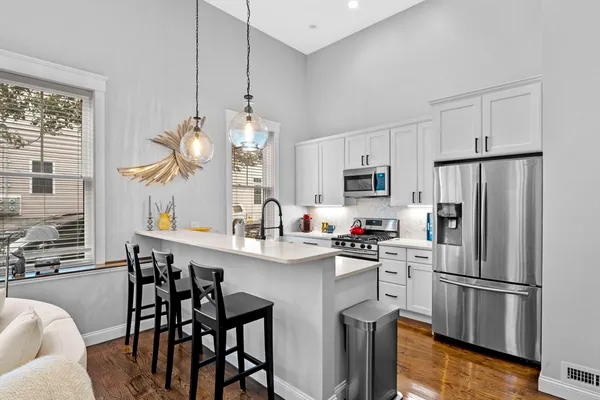 a kitchen with stainless steel appliances a refrigerator a stove a sink dishwasher and white cabinets with wooden floor