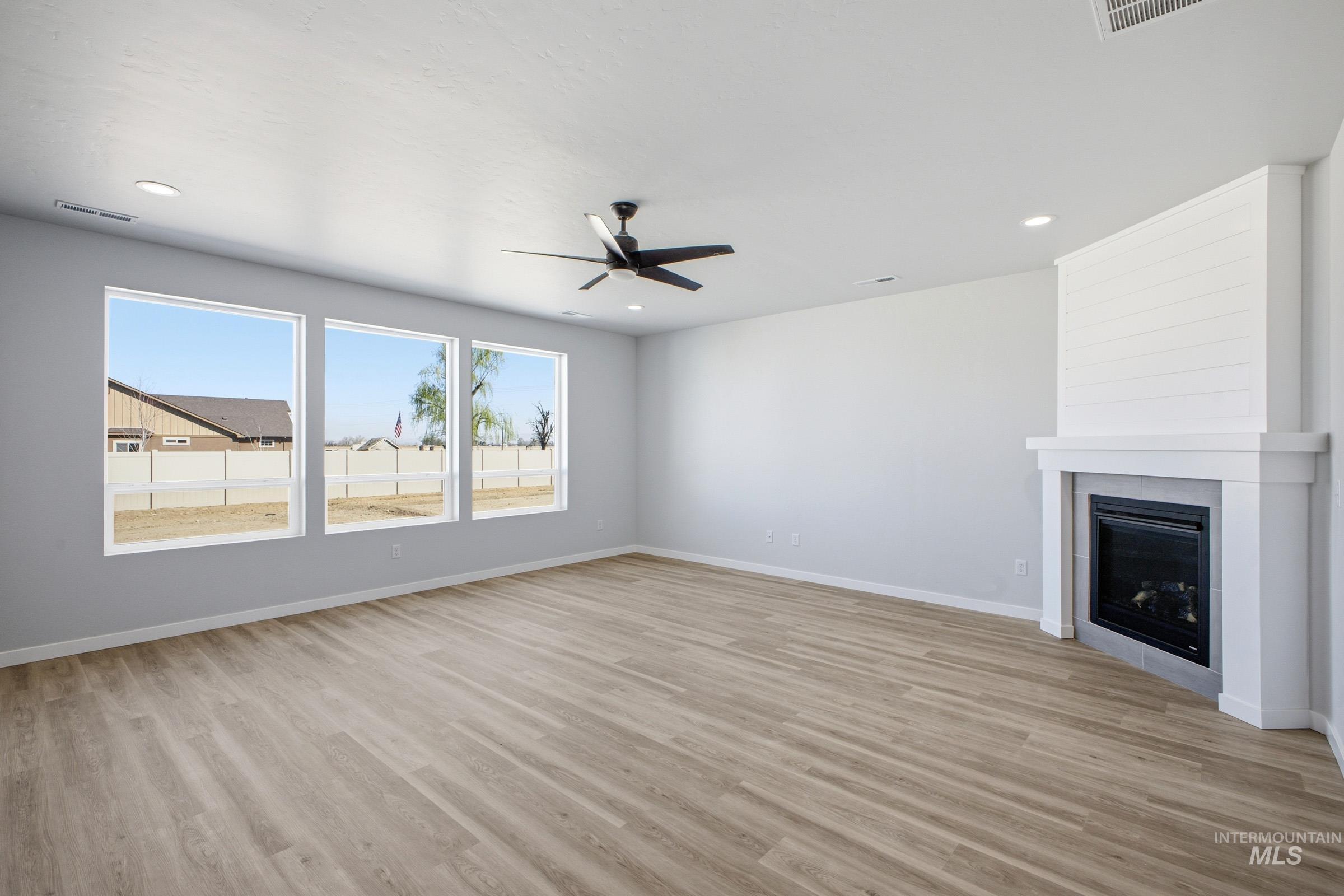 13633 Redway Court Caldwell, ID 83607 - Photo 8 of 29 Unfurnished living room featuring ceiling fan, a large fireplace, light wood-type flooring, and recessed lighting