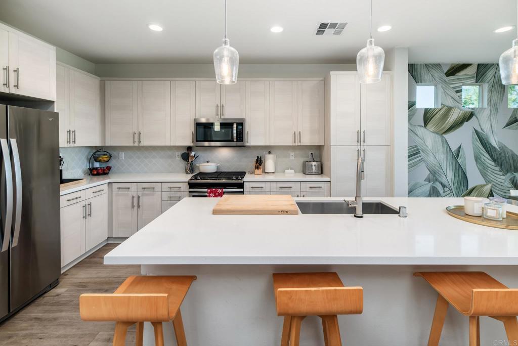 1244 Via Candelas Oceanside, CA 92056 - Photo 29 of 60 a kitchen with a sink a stove a refrigerator and white cabinets