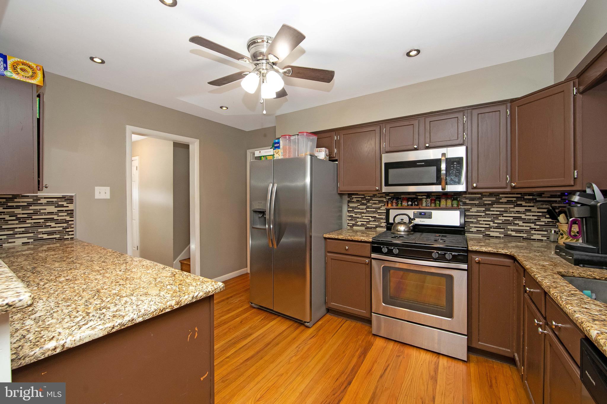 421 Yorkshire Road Cherry Hill, NJ 08034 - Photo 9 of 38 a kitchen with kitchen island granite countertop stainless steel appliances a stove cabinets and wooden floor