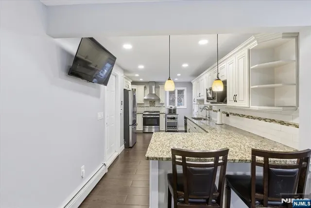 a kitchen with stainless steel appliances granite countertop a stove a refrigerator a microwave a sink a dining table and chairs with wooden floor
