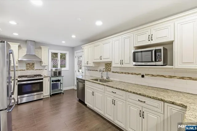 a kitchen with stainless steel appliances granite countertop a stove a sink and a microwave