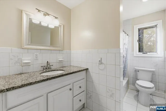 a bathroom with a granite countertop sink a toilet and mirror