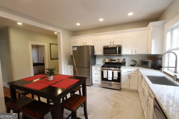 a kitchen with stainless steel appliances granite countertop a stove a refrigerator a microwave a sink and a dining table