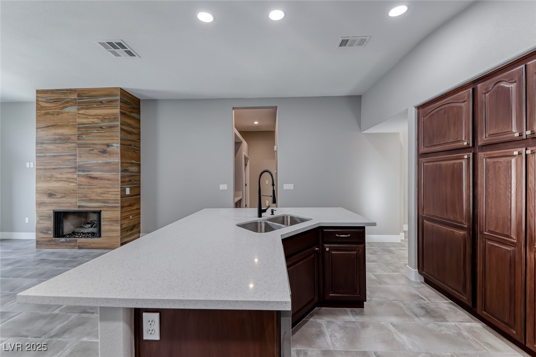2401 Flower Spring Street Las Vegas, NV 89134 - Photo 41 of 42 Kitchen with an island with sink, recessed lighting, a tiled fireplace, light stone counters, and open floor plan