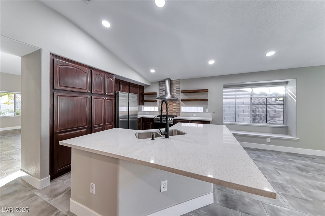 2401 Flower Spring Street Las Vegas, NV 89134 - Photo 18 of 42 Kitchen with open shelves, lofted ceiling, light stone counters, stainless steel appliances, and wall chimney exhaust hood