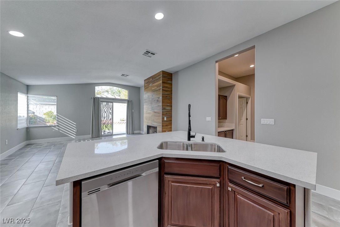 2401 Flower Spring Street Las Vegas, NV 89134 - Photo 42 of 42 Kitchen with stainless steel dishwasher, a kitchen island with sink, light stone countertops, light tile patterned floors, and open floor plan