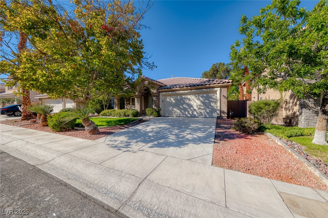 2401 Flower Spring Street Las Vegas, NV 89134 - Photo 3 of 42 View of front of property featuring concrete driveway, a tile roof, stucco siding, and a garage