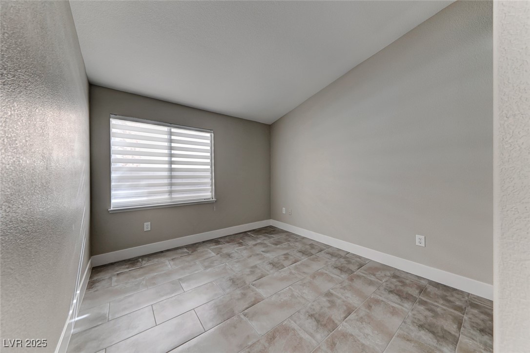 2401 Flower Spring Street Las Vegas, NV 89134 - Photo 31 of 42 Unfurnished room featuring a textured wall, vaulted ceiling, and light tile patterned floors