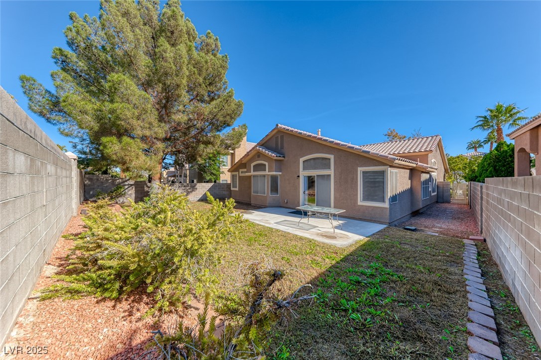 2401 Flower Spring Street Las Vegas, NV 89134 - Photo 39 of 42 Rear view of house featuring a fenced backyard, a tile roof, a patio, and stucco siding