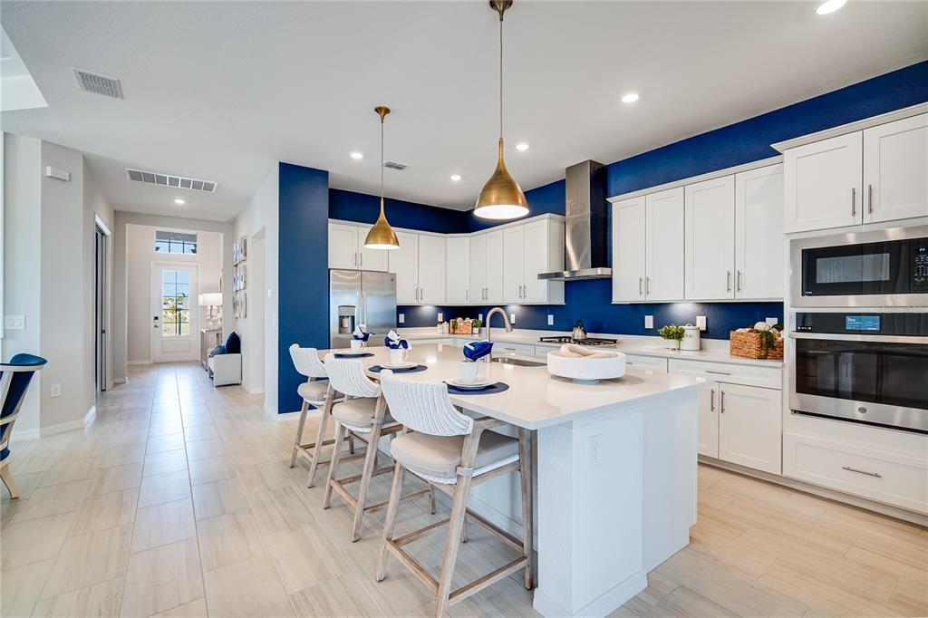 7165 Inlet Isles Lakewood Ranch, FL 34202 - Photo 7 of 26 a kitchen with stainless steel appliances kitchen island granite countertop a stove a sink a refrigerator and white cabinets with wooden floor