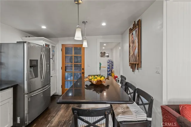 a kitchen with stainless steel appliances granite countertop a refrigerator a stove and a dining table with wooden floor