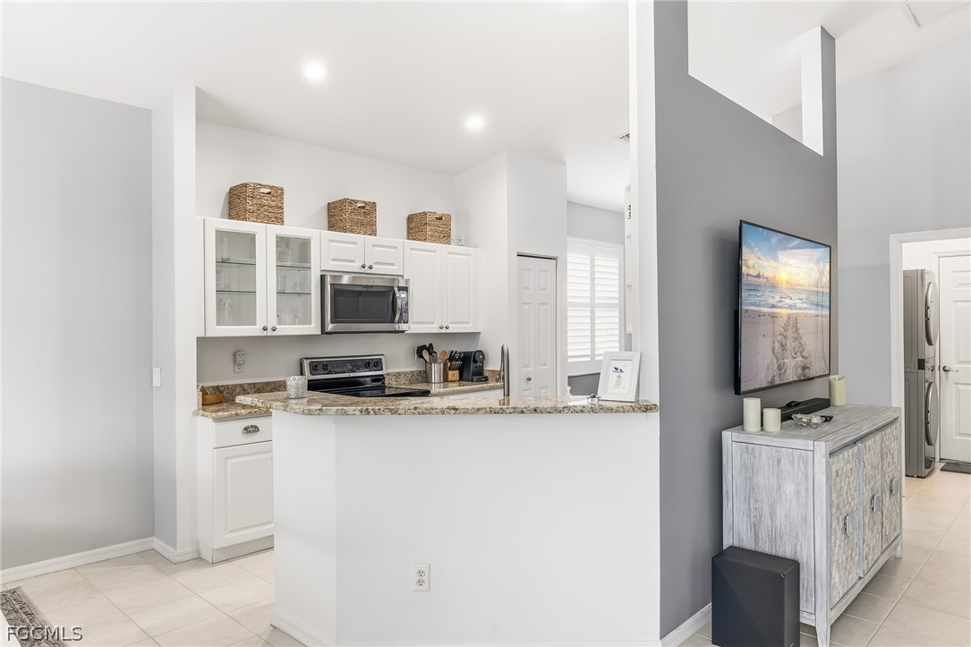 9004 Springview Loop Estero, FL 33928 - Photo 12 of 41 a kitchen with stainless steel appliances granite countertop a stove top oven a sink a refrigerator white cabinets and wooden floor