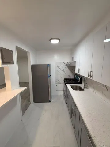 a kitchen with stainless steel appliances a white refrigerator a sink a stove and a refrigerator