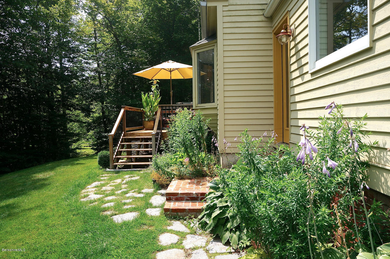 4 Stonebridge Way Tyringham, MA 01264 - Photo 38 of 40 a backyard of a house with table and chairs under an umbrella