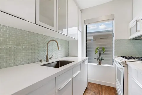 a kitchen with a refrigerator a faucet a sink and wooden floor