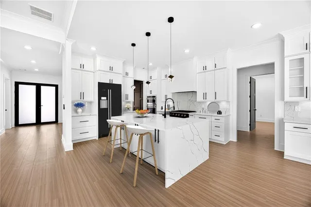a kitchen with stainless steel appliances kitchen island wooden floors stove and white cabinets