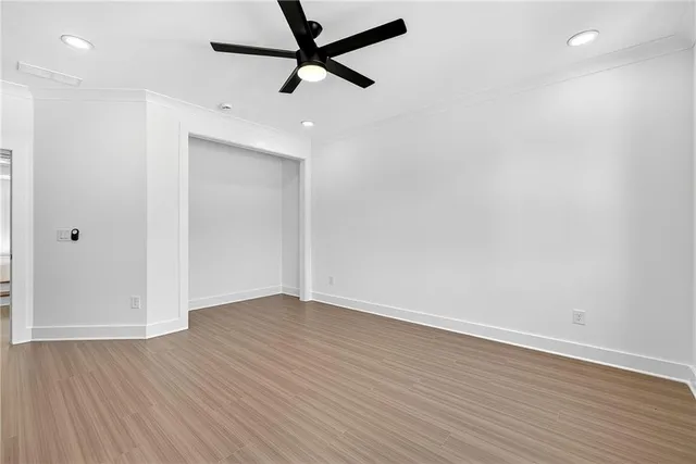 an empty room with wooden floor and a ceiling fan