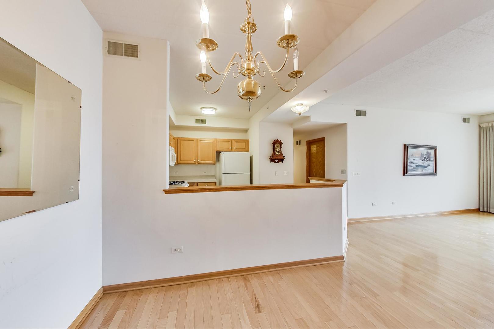 1761 Pavilion Way, Unit 306 Park Ridge, IL 60068 - Photo 5 of 19 a view of an empty room with chandelier fan and wooden floor