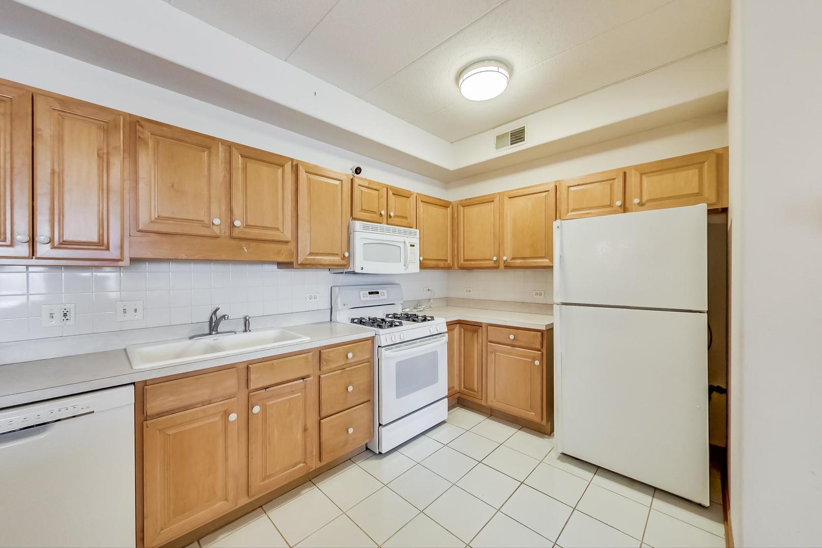 1761 Pavilion Way, Unit 306 Park Ridge, IL 60068 - Photo 7 of 19 a kitchen with a sink a refrigerator and cabinets