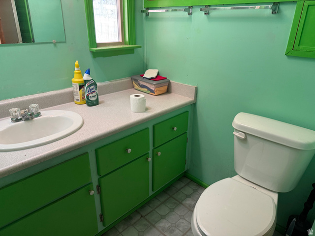 210 South State Street Moroni, UT 84646 - Photo 9 of 23 Bathroom featuring a white toilet, an integrated sink with a two-handle faucet, a vanity with green cabinetry, and a window with green trim