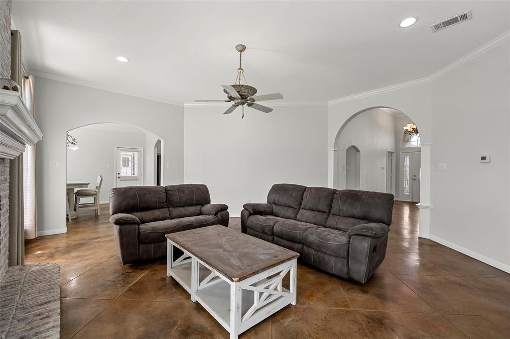 3696 Old Lorena Road Lorena, TX 76655 - Photo 8 of 27 Spacious living area featuring polished concrete flooring, arched doorways, a brick fireplace with a white mantel, recessed lighting, and crown molding
