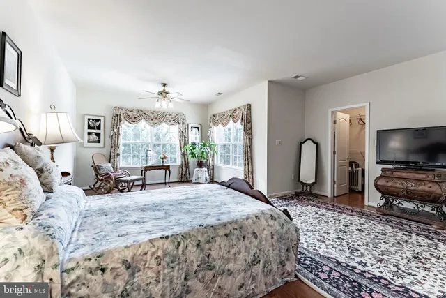 a spacious bedroom with a bed a large window and flat screen tv