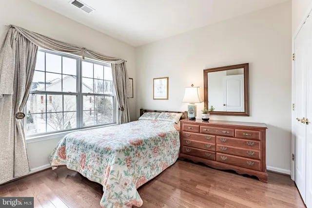 a bedroom with a bed and a dresser next to a window