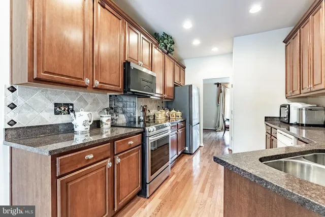 a kitchen with stainless steel appliances granite countertop a sink a stove and refrigerator