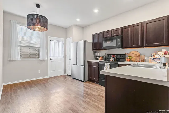 a kitchen with stainless steel appliances a refrigerator a stove a sink dishwasher and white cabinets with wooden floor