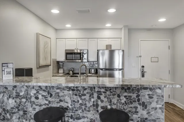 a kitchen with stainless steel appliances granite countertop a sink a stove a microwave a refrigerator and island