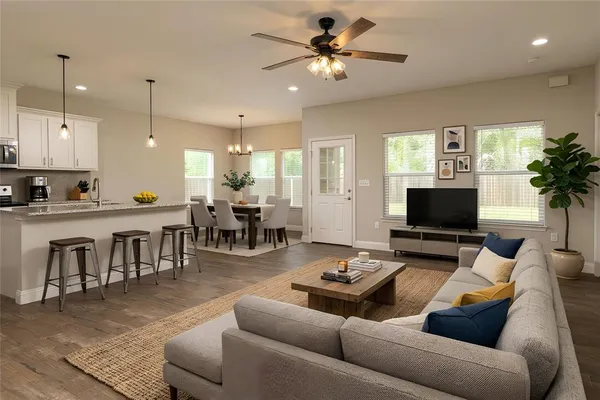 a living room with furniture kitchen view and a large window