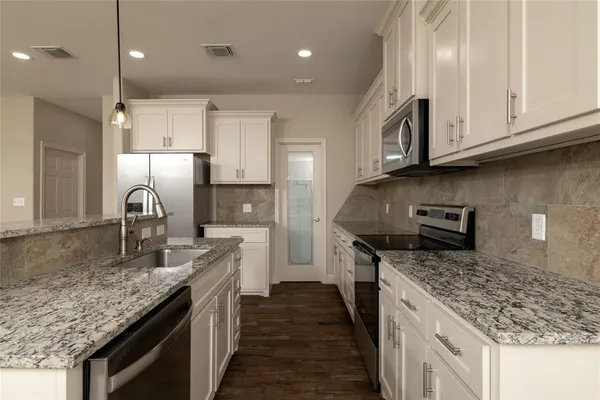 a kitchen with granite countertop stainless steel appliances and white cabinets