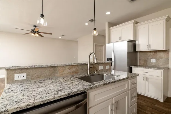 a kitchen with stainless steel appliances granite countertop a sink a refrigerator and cabinets