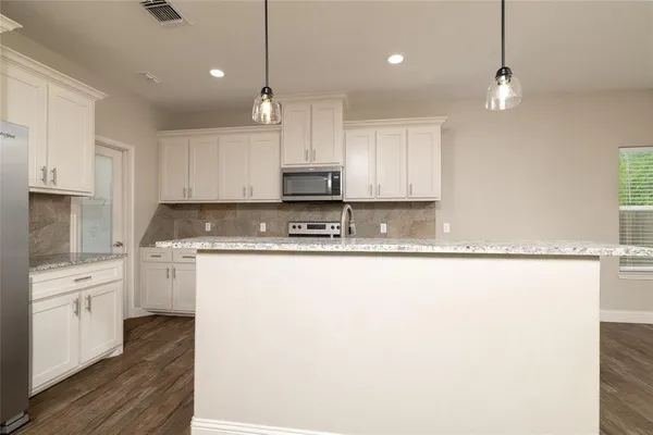 a kitchen with kitchen island granite countertop a sink cabinets and stainless steel appliances