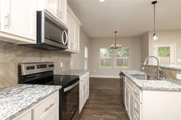a kitchen with stainless steel appliances granite countertop a sink stove microwave and refrigerator