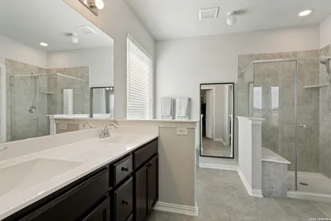 a bathroom with a double vanity sink mirror and shower