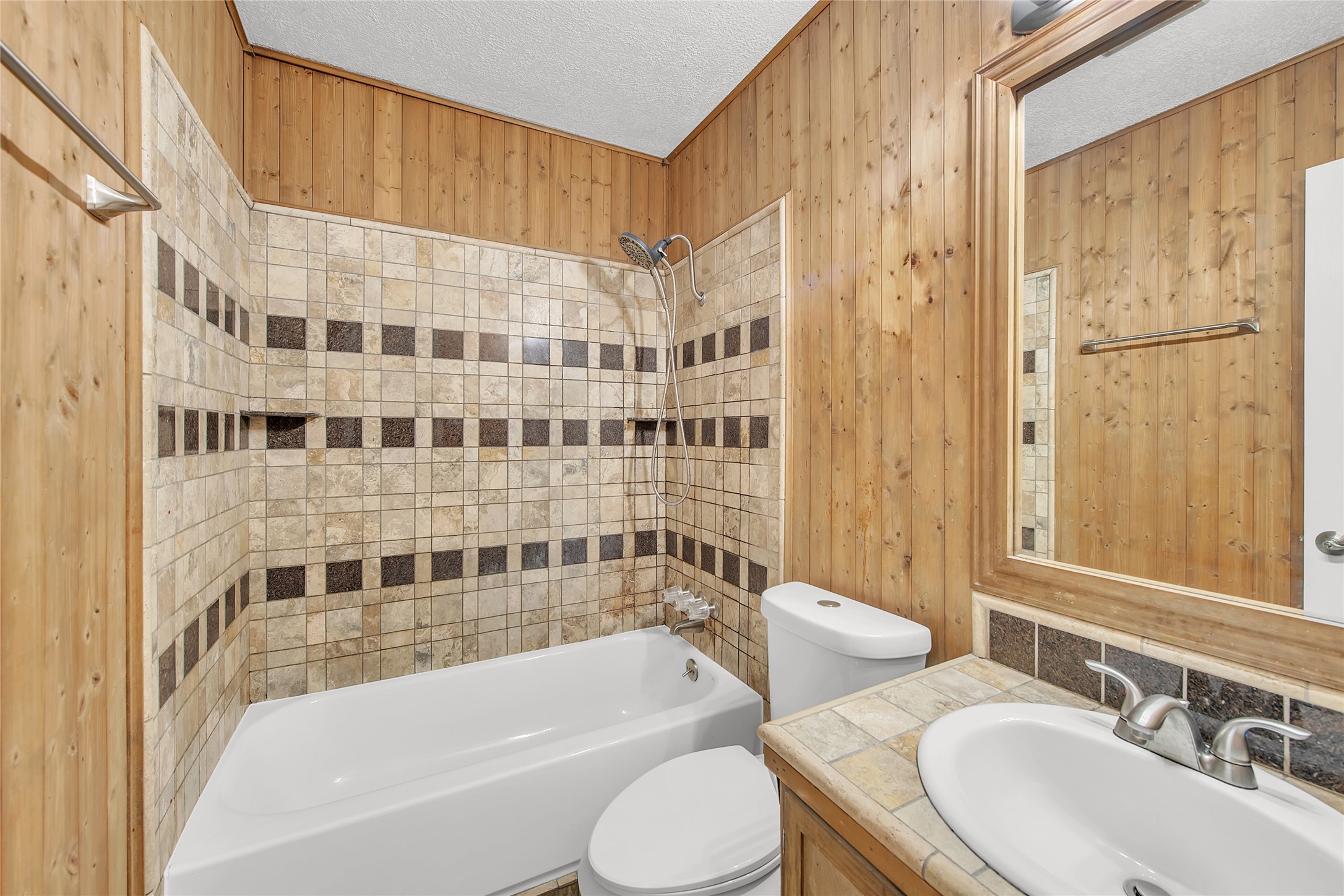 7209 Gunnison Pass Austin, TX 78724 - Photo 15 of 19 A well-appointed bathroom featuring rustic wood paneling and elegant tile work around the bathtub and vanity.