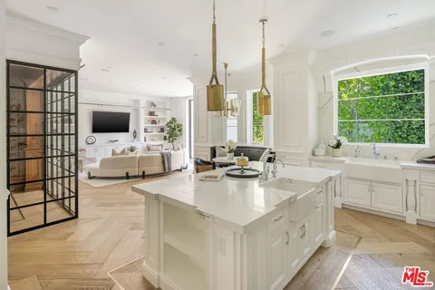 a large white kitchen with a large window and sink