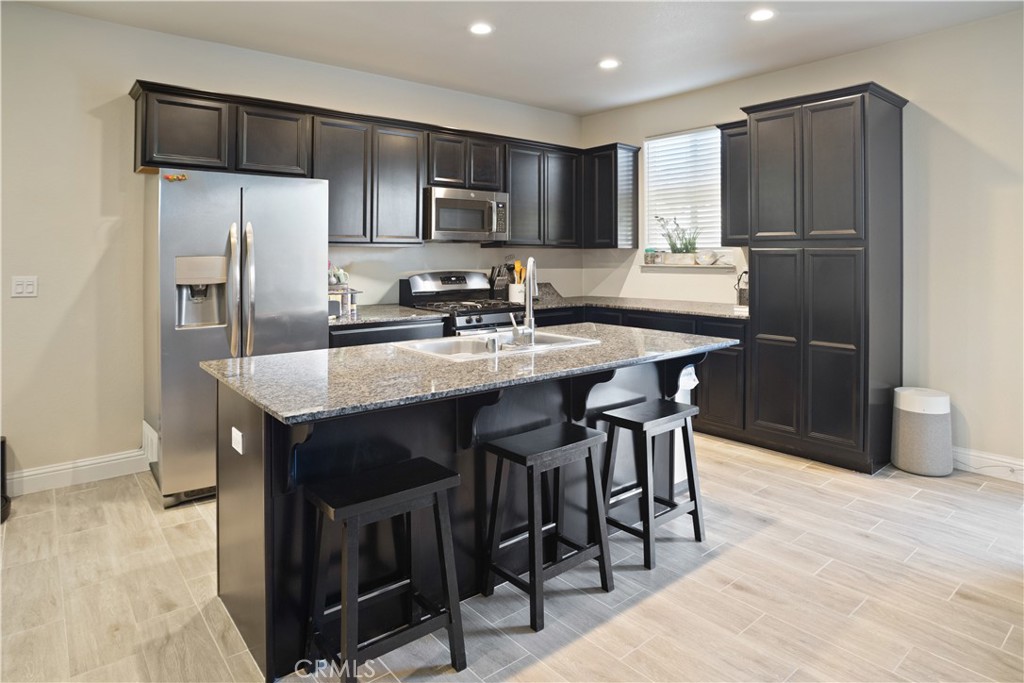 4440 Lindsey Lane Merced, CA 95348 - Photo 6 of 23 a kitchen with kitchen island granite countertop wooden cabinets and stainless steel appliances