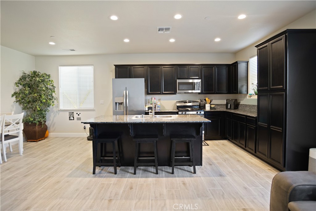 4440 Lindsey Lane Merced, CA 95348 - Photo 8 of 23 a kitchen with stainless steel appliances kitchen island granite countertop a refrigerator a stove a sink and a dining table with wooden floor