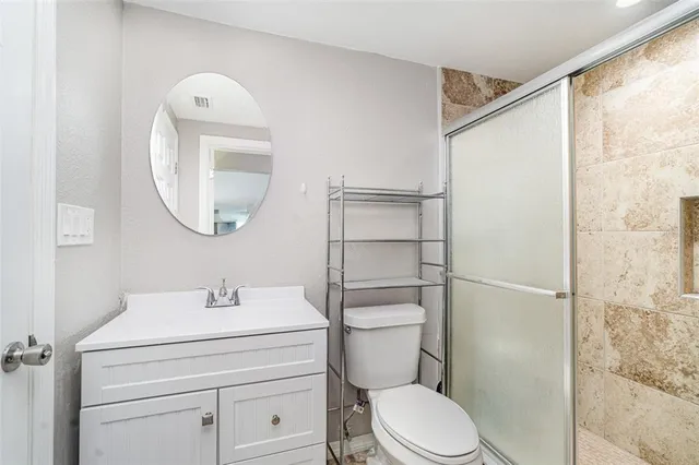 a bathroom with a toilet sink vanity and mirror