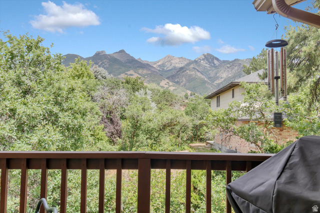 2863 Fallentine Road Sandy, UT 84093 - Photo 48 of 48 Outdoor deck with wood railing, offering a mountain backdrop and lush green trees