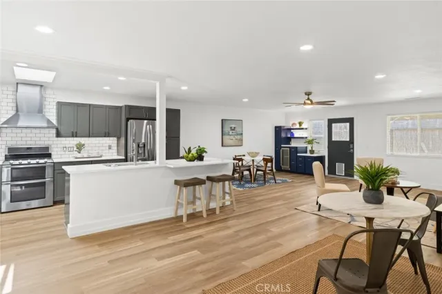 a kitchen with stainless steel appliances kitchen island granite countertop a table chairs and a refrigerator